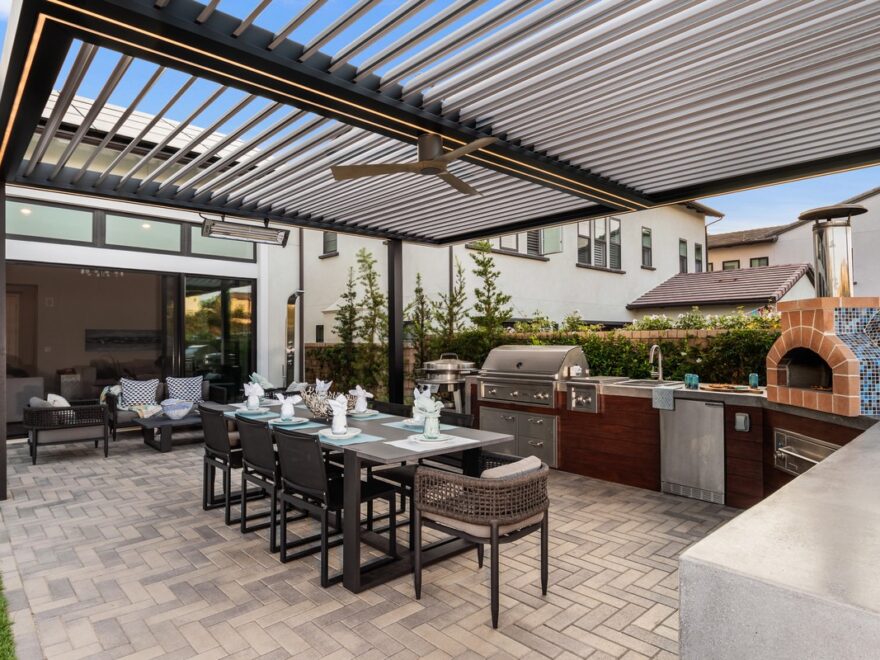 Northern Virginia outdoor living with louvered pergola, outdoor kitchen, built-in grill, pizza oven, and seamless connection to indoor living space