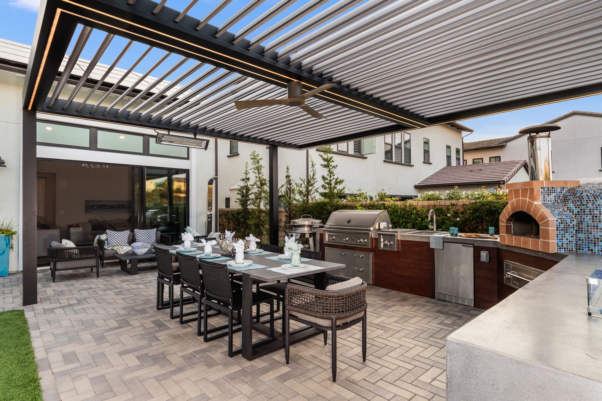 Northern Virginia outdoor living with louvered pergola, outdoor kitchen, built-in grill, pizza oven, and seamless connection to indoor living space