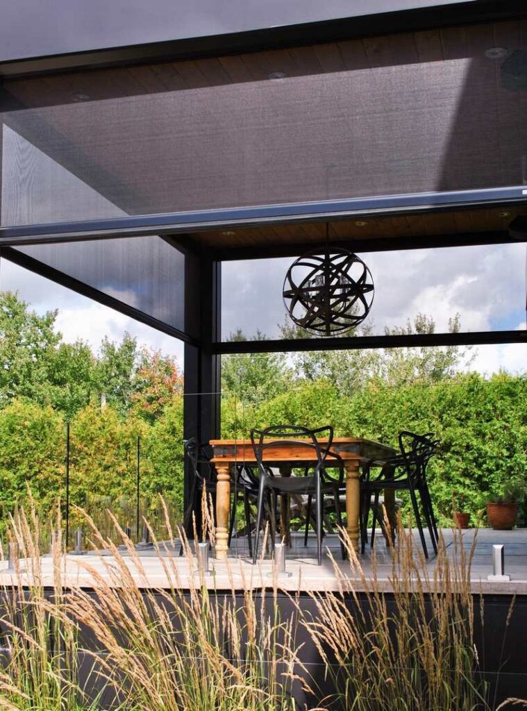 Outdoor dining area with motorized patio screen shades for added comfort